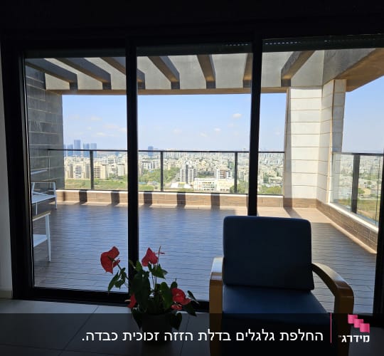 מרפסת עם נוף עירוני דרך חלון זכוכית
